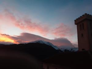 a sunset with a clock tower and a mountain at Villë Dallëndyshe 