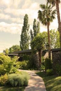 a garden with palm trees and a building at Susana Balbo Winemaker´s House in Ciudad Lujan de Cuyo