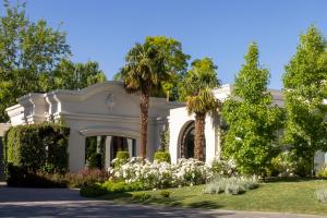 een wit huis met palmbomen en bloemen bij Susana Balbo Winemaker´s House in Ciudad Lujan de Cuyo