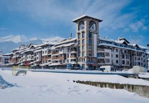 a large building with a clock tower in the snow at Bansko Royal Towers Private Apartment V&K in Bansko