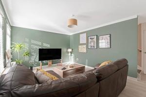 a living room with a brown couch and a tv at Stylish 2-Bed House Private Driveway in Glasgow