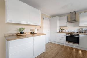 a kitchen with white cabinets and a wooden floor at Stylish 2-Bed House Private Driveway in Glasgow
