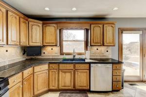 cocina con armarios de madera, fregadero y ventana en Spacious Derby Home with Hot Tub, en Louisville