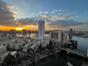 a sunset over a city with a river and buildings at Nile view apartment in Cairo