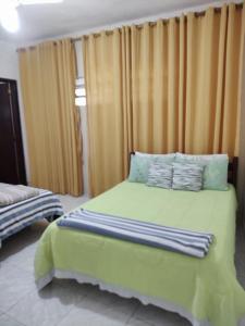 a bedroom with a bed with green sheets and pillows at Espaço 579 in Miguel Pereira