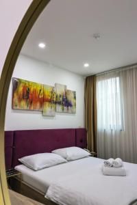 a bedroom with a bed with three paintings on the wall at Hotel National in Zagreb