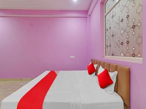 a pink room with a bed with red pillows at Srv Inn in Nilmatha