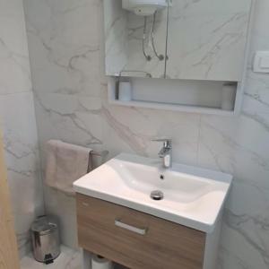 La salle de bains blanche est pourvue d'un lavabo et d'un miroir. dans l'établissement Apartment Parenzana Bibali 65 A 52460-Buje, à Buje