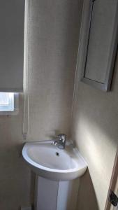 La salle de bains est pourvue d'un lavabo blanc et d'un miroir. dans l'établissement 51 Oaklands thorness bay Parkdean holiday resort, à Cowes