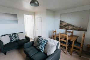 a living room with a couch and a dining room table at SUMMER VIEW - Escape to our Cosy Cottage with Log Burner in Drigg