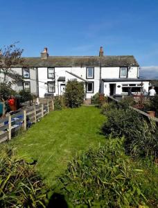 a house with a green yard in front of it at SUMMER VIEW - Escape to our Cosy Cottage with Log Burner in Drigg