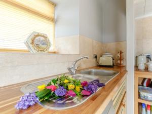 a kitchen sink with a bouquet of flowers on it at 1 Bed in Wootton Under Edge EARBA in Charfield