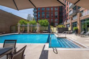 a swimming pool with chairs and a table and a building at Reston 1br w pool wd close to shopping mall WDC-828 in Reston