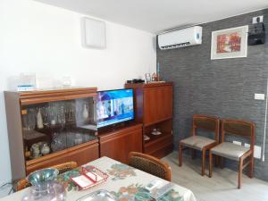 ein Wohnzimmer mit einem TV, einem Tisch und Stühlen in der Unterkunft B&B La Zia - Manoppello in Manoppello