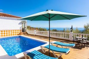 a swimming pool with two chairs and an umbrella at Villa Casa Leo in Frigiliana