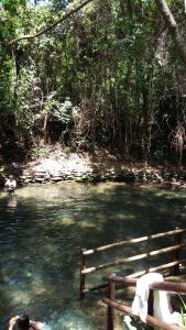 une personne assise sur un banc dans une rivière dans l'établissement Águas da Serra Apart Service - acesso ao rio e vista pra serra, à Rio Quente