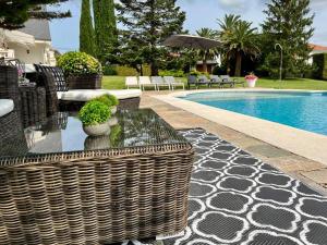 a swimming pool with a wicker patio furniture next to a swimming pool at Autentico lujo, Villa Stylish Host Cantabria. in Camargo