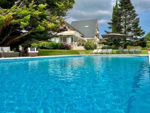 a large blue swimming pool in front of a house at Autentico lujo, Villa Stylish Host Cantabria. in Camargo