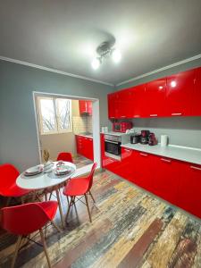 a kitchen with red cabinets and a table and chairs at RED Dhomes . Near Nymphaea in Oradea