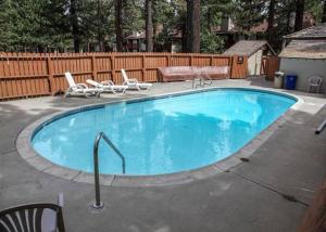 a large swimming pool with chairs and a fence at Cozy Cabin-Style Condo in Central Location in Mammoth Lakes