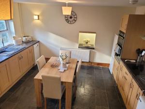 a kitchen with a wooden table with chairs and a dining room at Cosy modern cottage by the sea, heart of snowdonia in Llwyngwril