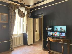 sala de estar con TV, mesa y ventana en Palazzo Montesi, en Mombaroccio