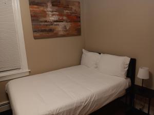 The Top-Floor at Centerdale Village Room B* Private Room في North Providence: غرفة نوم بسرير ذو شراشف ووسائد بيضاء