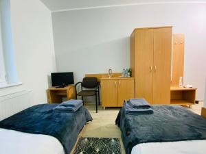 a room with two beds and a desk with a computer at HOTEL MILO - Noclegi Bartoszyce in Bartoszyce