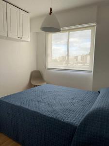 ein Schlafzimmer mit einem blauen Bett und einem Fenster in der Unterkunft Muy cómodo y trendy in Montevideo