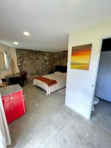 1 dormitorio con 1 cama y 1 maleta roja en Cabaña El Fantasio en Villa Carlos Paz