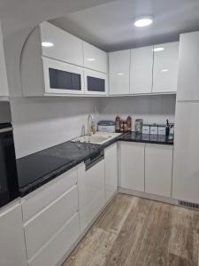 una cocina con armarios blancos y encimeras negras en small apartment for two en Brus