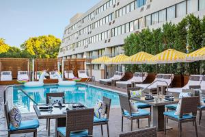 un patio con tavoli, sedie e piscina di Hotel Dena, Pasadena Los Angeles, a Tribute Portfolio Hotel a Pasadena