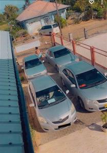 tres autos estacionados en un estacionamiento junto a una valla en Kapowlito Real Estate Casa Hoopweg en Paramaribo