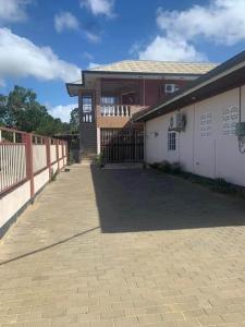 ein Gebäude mit einem Zaun und einer steinernen Einfahrt in der Unterkunft Kapowlito Real Estate Casa Hoopweg in Paramaribo