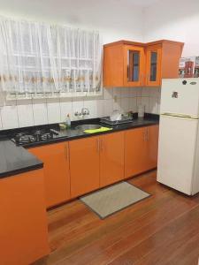 cocina con armarios naranjas y nevera blanca en Kapowlito Real Estate Casa Hoopweg, en Paramaribo