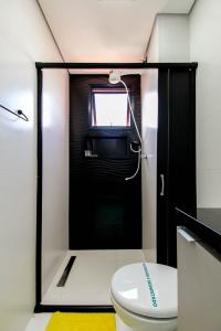 a bathroom with a toilet and a black door at LF101 - Studio decorado no Tatuapé (Metrô a 250m) in Sao Paulo