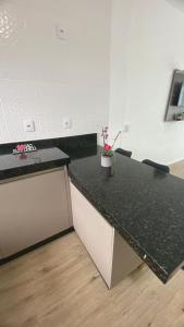 a kitchen with a black counter top with a vase of flowers at Apartamento na praia de Ubatuba, São Francisco do sul in São Francisco do Sul +8 photos