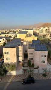 um carro preto estacionado em frente a um edifício com painéis solares em شقق الرفيق الفندقية em Aqaba