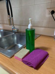 a green bottle of soap and a purple towel on a sink at Casa di Bea in Merate