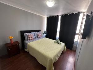 um pequeno quarto com uma cama com uma colcha amarela em Apartamentos Orquídea Suite em Santiago