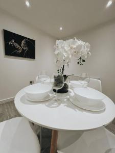 a white table with white plates and wine glasses at Oldbury Heritage Hideaway! in Birmingham