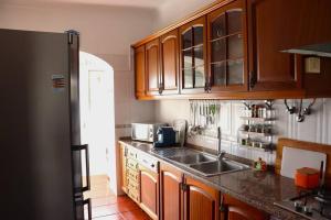 cocina con armarios de madera, fregadero y nevera en Judith House - Amadora Este, en Amadora