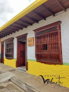 un edificio amarillo y blanco con ventanas. en Volarte Hostal en Jardín