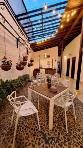 a patio with a wooden table and white chairs at Volarte Hostal in Jardin