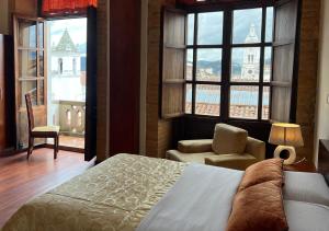 a bedroom with a bed and a chair and windows at Floré Hotel Boutique Cuenca in Cuenca