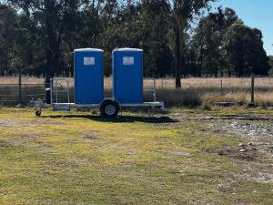 two blue portable toilets sitting in a field at Thagoona Shady River Camp in Thagoona