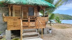 a wooden hut on the beach with stairs leading to it at NATUAS BEACH in El Nido