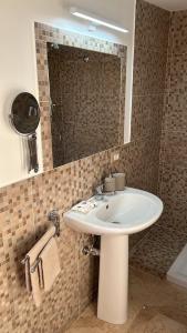La salle de bains est pourvue d'un lavabo blanc et d'un miroir. dans l'établissement Il piacere appartaments, à Caltagirone