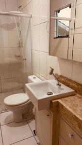 a white bathroom with a toilet and a sink at Casa grande em bairro tranquilo in Pato Branco