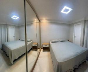 1 Schlafzimmer mit 2 Betten und einem Spiegel in der Unterkunft Um passo do mar in Guarapari